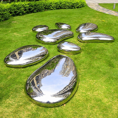 O seixo lustrado alto do jardim de Gnee dá forma à escultura de aço inoxidável para o gramado